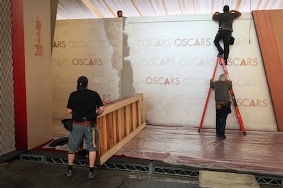 Plusieurs travailleurs s'efforcent de préparer le tapis rouge de l'Oscar, à Hollywood Boulevard, à Los Angeles, en Californie, le 26 février 2025.