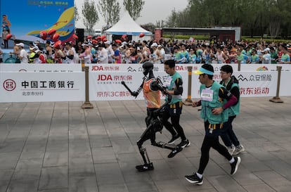 Le robot humanoïde Tiangong court avec ses techniciens à Pékin, ce samedi.