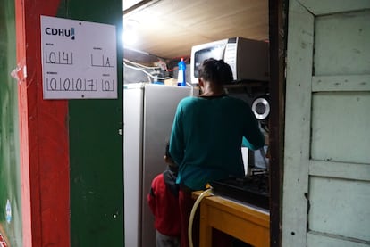 Deux Santos et ses petits-fils de cinq ans dans la maison où ils vivent, marqués d'une affiche de la société de logement et de développement urbain.