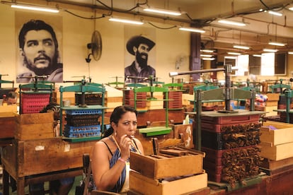 Une femme fume un haban tout en travaillant comme une touche dans l'usine de tabac de La Corona.
